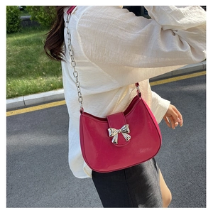 Detail of rose red crescent shoulder bag with silver bow buckle and chain strap