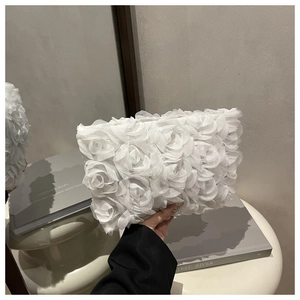 Detail of elegant white evening clutch bag featuring 3D organza rose floral textures