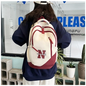 Rear view of model wearing the large white and red canvas backpack with N logo patch