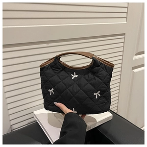Close-up of quilted black handbag with silver sequin bows and brown leather handles