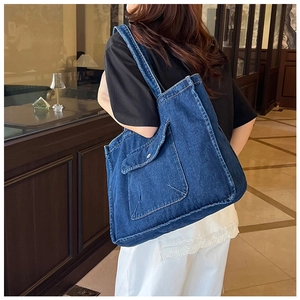 Detailed view of the dark blue denim tote bag with front flap pocket and contrast stitching