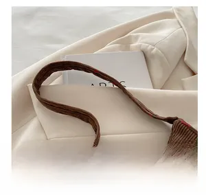 Détail de la bandoulière confortable en velours côtelé sur un sac marron aux fraises