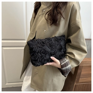 Detailed view of black 3D lace rose petals on a stylish women's evening clutch bag