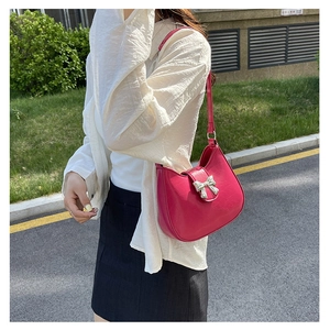Detailed view of fuchsia leather handbag featuring a polished silver metal bow buckle