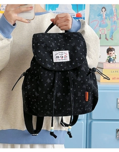 Detail of black corduroy backpack featuring embossed butterfly patterns and drawstring closure