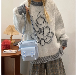 Detail view of the light blue canvas crossbody bag with double-button closure and strap