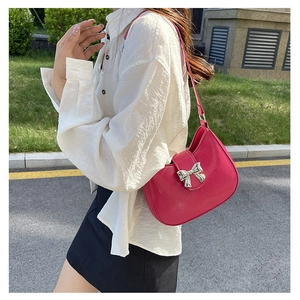 Close-up of bright pink shoulder bag with metallic silver bow clasp and glossy finish