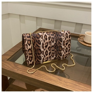 Détail du sac à main léopard avec chaîne dorée sur une table en verre élégante