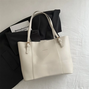 Detailed close-up of cream leather tote bag with gold buckle and fashion text print