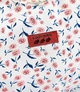 Detail of white floral bag with pink blossoms and red LUOYINING brand tag stitching