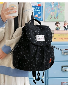 Detail of corduroy backpack with bow pattern, drawstring closure and blue bead accents