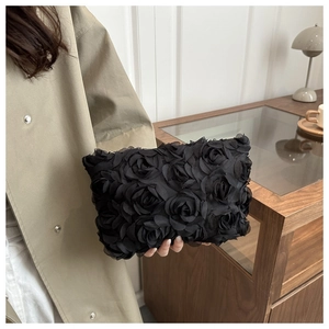 Close-up of black 3D rose fabric clutch with elegant lace texture for evening wear
