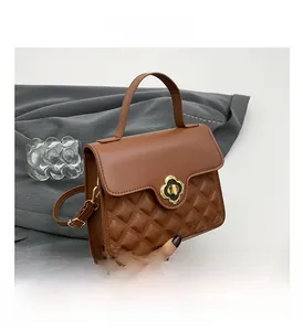 Detail of caramel brown quilted handbag with elegant gold flower twist lock and top handle
