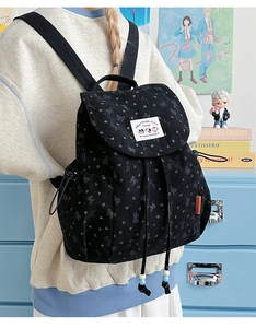 Detail of black corduroy backpack with heart prints and decorative character patch