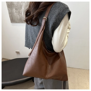 Borsa Hobo marrone indossata da modella con tracolla regolabile e texture in pelle