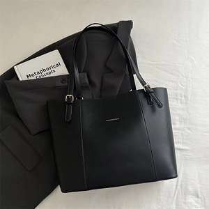 Close-up of black matte tote bag with white fashion text on minimalist fabric background
