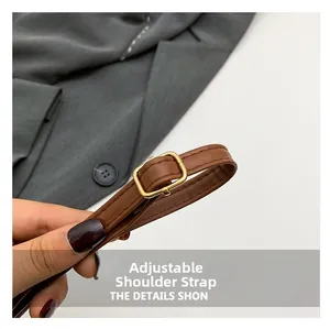 Close-up of adjustable brown leather shoulder strap with gold metal buckle and neat stitching