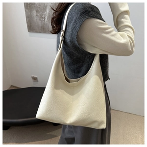 Dettaglio della borsa tote in ecopelle color crema con trama martellata e tracolla larga