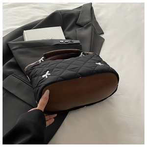 Fashionable black quilted handbag with white bow embroidery on a black blazer jacket