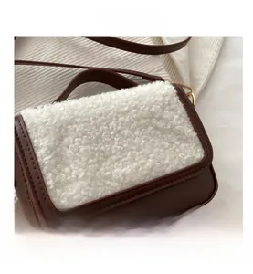 Close-up detail of small square crossbody bag with brown leather and white faux shearling
