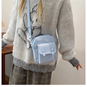 Detail of light blue minimalist crossbody phone bag worn by a model in a modern home setting