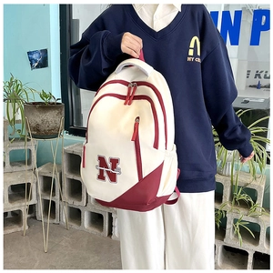 Detail view of large-capacity beige and burgundy canvas travel backpack with N embroidery
