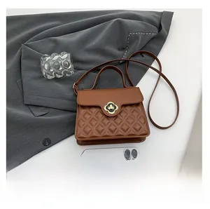 Detail view of brown quilted handbag with gold flower lock and shoulder strap