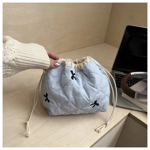 Macro shot of light blue quilted drawstring bag featuring black butterfly embroidery details