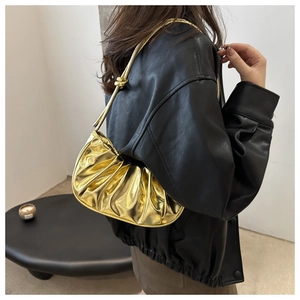 Sac à bandoulière doré métallisé avec plis porté avec une veste en cuir noir