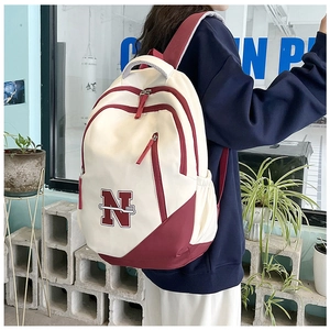 Detail view of the beige and burgundy backpack with N patch and multi-pocket layout