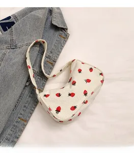 Detailed close-up of white corduroy underarm bag featuring vibrant red strawberry patterns