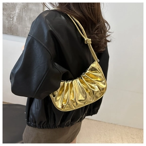 Détail du sac croissant doré métallisé plissé avec bandoulière élégante sur modèle