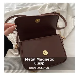 Detail showing the gold magnetic snap closure and brown matte leather flap of the handbag
