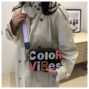 Dettaglio della borsa a tracolla nera con cinturino viola e patch Color Vibes