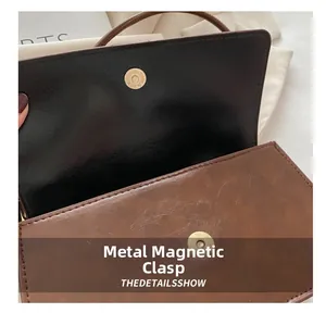 Detail der braunen Vintage-Umhängetasche mit dem goldenen Metall-Magnetverschluss der Klappe