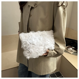 Detailed macro shot of 3D white organza rose flowers on a chic evening clutch bag