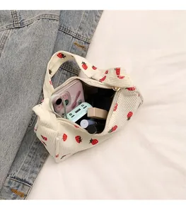 Detail showing white corduroy strawberry print bag interior capacity with cosmetic items