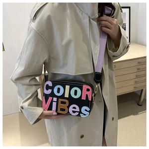 Dettaglio della borsa a tracolla nera con scritte colorate a rilievo e tracolla viola