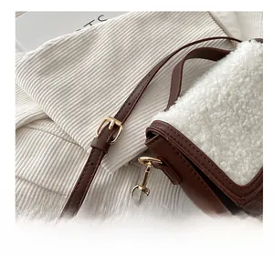 Detail of adjustable golden metal buckle and brown leather strap on crossbody bag