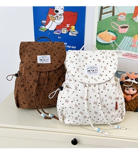 Detail of corduroy backpacks with heart and bow patterns in brown and cream colors