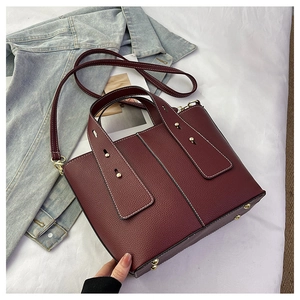 Detail of burgundy pebbled leather tote with metallic studs and durable base studs