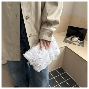 Detail of white evening clutch bag featuring 3D mesh rose floral texture and soft finish