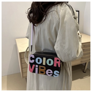 Dettaglio borsa a tracolla nera con lettere COLOR VIBES colorate e doppia chiusura lampo