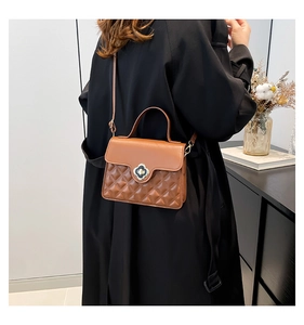 Brown quilted leather crossbody bag with golden clover lock shown on model with black coat