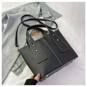 Detail of black lychee grain leather tote with white stitching and gold hardware accents