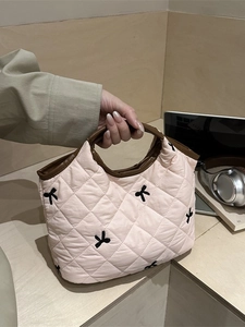 Pink quilted handbag with black bow pattern and brown top handles for daily casual use