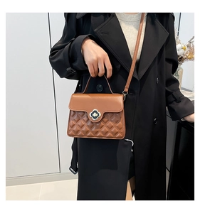 Brown quilted leather handbag with clover metal lock worn by a model in a black coat