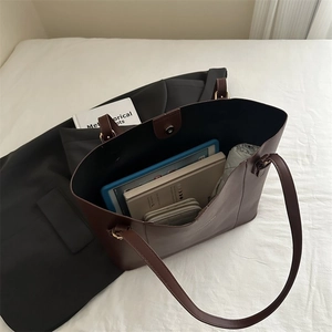 Detail view of large brown leather tote bag with tablet and books inside for storage capacity