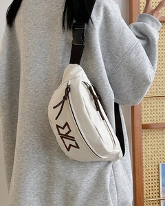 Detail view of white leather waist bag with brown logo and adjustable crossbody strap