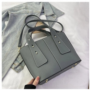 Detail view of grey litchi grain leather bucket bag with white contrast stitching and gold feet